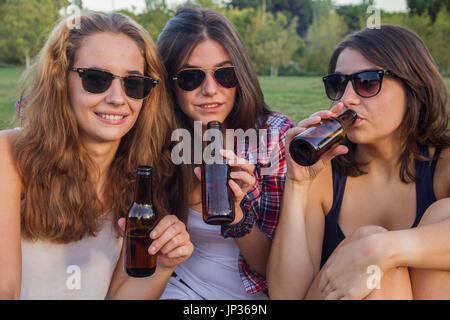 Ragazze godendo nel parco. Essi sono gli amici di celebrare le festività avente una buona volta a bere birra in un parco. Foto Stock