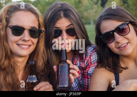 Ragazze godendo nel parco. Essi sono gli amici di celebrare le festività avente una buona volta a bere birra in un parco. Foto Stock