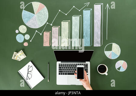 Vista superiore della persona di business utilizzando dispositivi digitali a workplace con grafici colorati, home concetto di ufficio Foto Stock