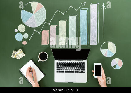 Vista superiore della persona di business utilizzando dispositivi digitali a workplace con grafici colorati, home concetto di ufficio Foto Stock