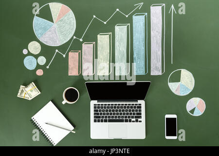 Vista superiore del computer portatile e i grafici di business con la tazza di caffè e lo smartphone, piccolo ufficio concetto Foto Stock