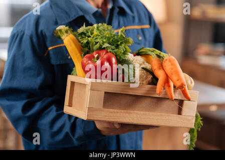 Neat nice corriere azienda una scatola piena di cibi sani Foto Stock