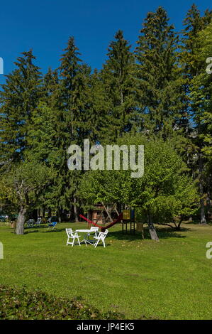 Veduta autunnale verso il giardino pubblico con tavolo da picnic a sedia prato, albero e open-air kindergarten, Cortina d'Ampezzo, Dolomiti, le Alpi, Veneto, Ital Foto Stock