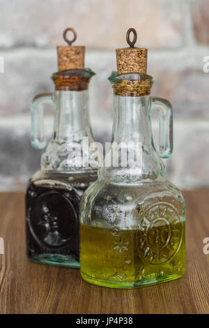 Olio e aceto balsamico di bottiglie di vetro con beccucci in mattone rustico sfondo a parete Foto Stock
