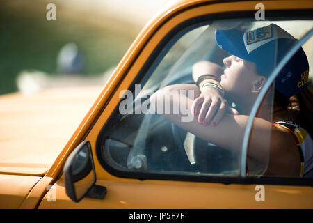 Giovane donna seduta nella cabina di un'auto. Foto Stock