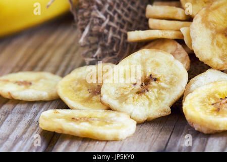 In casa banana chips (essiccato fritte e fette di banana) su sfondo di legno Foto Stock