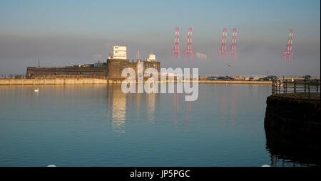 Gigantesca gru portuali a Seaforth container terminal che sorge fuori della nebbia dietro Fort Pesce persico Rock, New Brighton Foto Stock