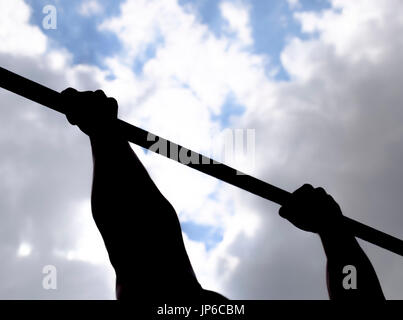 Silhouette di mani su una barra orizzontale. Le mani sulla barra di close-up. L'uomo tira se stesso sulla barra. Sport all'aria fresca. B orizzontale Foto Stock