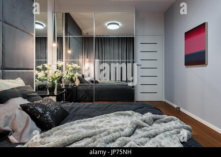 Elegante camera con letto matrimoniale, armadio a specchio e tv Foto stock  - Alamy