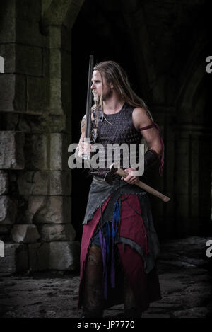 Medieval rievocazione viking warrior soldato, giovane con i capelli lunghi e la barba a treccia e tatuaggio indossando viking Foto Stock