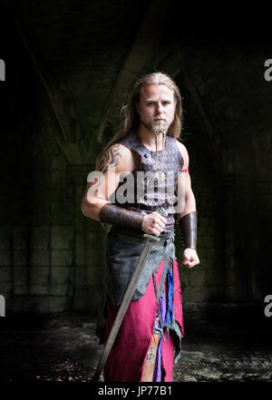 Medieval rievocazione viking warrior soldato, giovane con i capelli lunghi e la barba a treccia e tatuaggio indossando viking Foto Stock