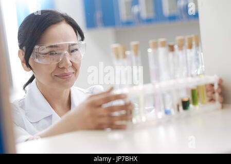 Smart positivo donna mettendo le provette per la prova sul ripiano Foto Stock