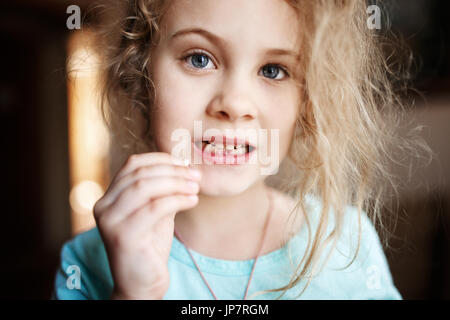 Ragazza sorridente azienda mancante dente di latte, vicino la foto. Foto Stock