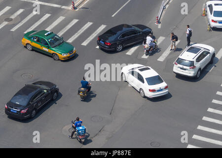 Tipico di Pechino caotico traffico della strada con vetture, ciclomotori e pedoni tutte convergenti su ampi boulevard intersezione Foto Stock