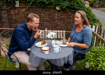 Una madre e figlio gustare tè e torte in un bar giardino, Fulking, Sussex, Regno Unito Foto Stock