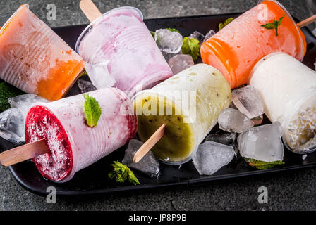 Sana dessert estivo. Ice Cream popsicles. Congelati succhi di frutta tropicali, frullati mirtilli. Uve secche di Corinto, arancio, mango, kiwi, banana, noce di cocco, lampone Foto Stock