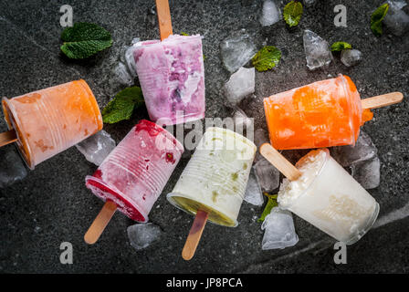 Sana dessert estivo. Ice Cream popsicles. Congelati succhi di frutta tropicali, frullati mirtilli. Uve secche di Corinto, arancio, mango, kiwi, banana, noce di cocco, lampone Foto Stock