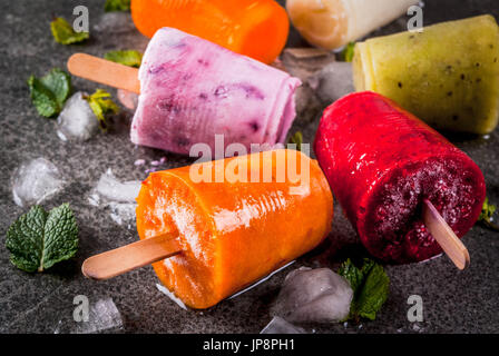 Sana dessert estivo. Ice Cream popsicles. Congelati succhi di frutta tropicali, frullati mirtilli. Uve secche di Corinto, arancio, mango, kiwi, banana, noce di cocco, lampone Foto Stock