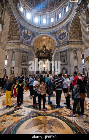 Vista verticale di turisti lokking presso San Pietro tomba all'interno della Basilica di San Pietro in Vaticano a Roma. Foto Stock