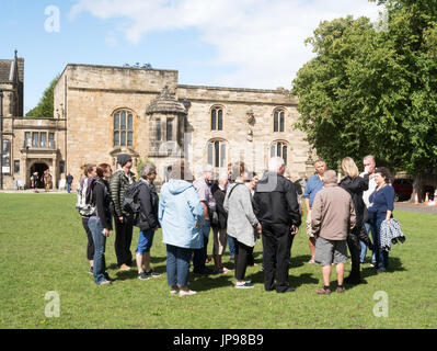 Una guida turistica e il gruppo di visitatori al di fuori dell Università di Durham libreria sul palazzo verde, Durham, England, Regno Unito Foto Stock