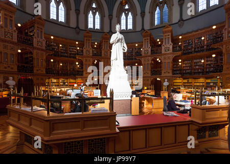 La principale sala di lettura della biblioteca del parlamento con una statua in marmo bianco della regina Victoria nel centro all'interno del blocco centrale. Foto Stock