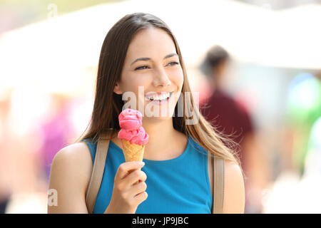 Felice ragazza camminare e trattenimento di un gelato alla fragola in strada Foto Stock