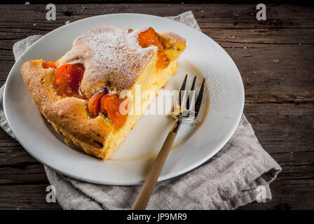 In casa autunno e estate dolci cotti al forno. Pan di Spagna con le albicocche. Tagliato a pezzi, la piastra forcella. Sul vecchio rustico in legno tavolo. Spazio di copia Foto Stock