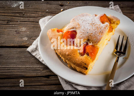 In casa autunno e estate dolci cotti al forno. Pan di Spagna con le albicocche. Tagliato a pezzi, la piastra forcella. Sul vecchio rustico in legno tavolo. Spazio di copia Foto Stock