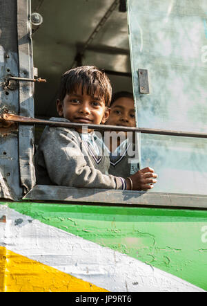 Un ragazzo con la finestra aperta di una scuola bus, Delhi, India. Foto Stock