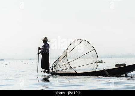 Lago Inle, MYANMAR - 15 febbraio 2014: pescatore birmano sulla barca di bambù per la cattura di pesce in modo tradizionale con la rete a mano. Foto Stock