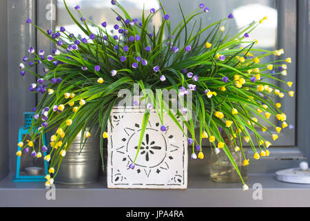 Decorativi fiori artificiali sul davanzale della finestra Foto Stock