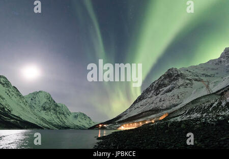 Le luci del nord e la luna riflessa nel mare di illuminare la cima innevata dell'Lyngseidet Alpi Lyngen Tromsø Norvegia Europa Foto Stock