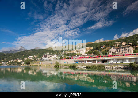 Bernina Express treno corre attraverso il villaggio di St.Moritz Circondato da lago Cantone dei Grigioni Engadina Svizzera Europa Foto Stock