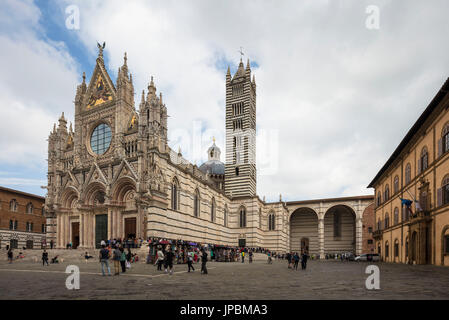 La bianca facciata in marmo e le decorazioni artistiche della storica cattedrale di Siena Toscana Italia Europa Foto Stock