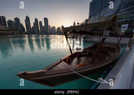 Uno dei battelli turistici di Burj Khalifa lago al tramonto, e sullo sfondo i grattacieli di Dubai. Emirati Arabi Uniti Foto Stock