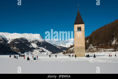 Il campanile della chiesa vecchia del Comune di Curon Venosta, ora sotto il lago di Resia in inverno, con il lago congelato e coperto di neve, Trentino Alto Adige, Italia Foto Stock