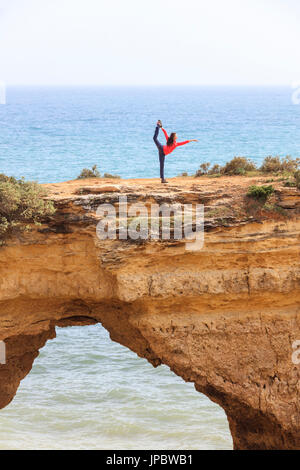 Donna ginnastica pratiche sulle scogliere rocciose Albandeira Lagoa comune Algarve Portogallo Europa Foto Stock