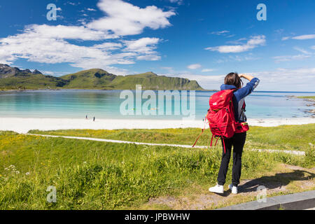 Fotografo in azione nel verde dei prati circondati da mare turchese e sabbia fine Ramberg Isole Lofoten in Norvegia Europa Foto Stock