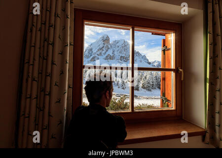 Un uomo si ammira il Sass de Putia circondato da neve dal vetro di una finestra il Passo delle Erbe Val di Funes Alto Adige Italia Europa Foto Stock