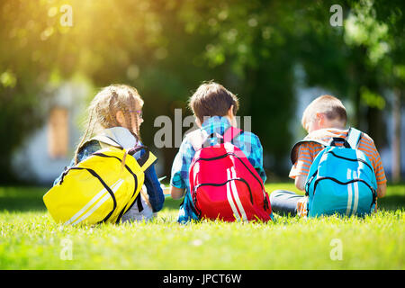 I bambini con zaini in piedi nel parco vicino alla scuola Foto Stock