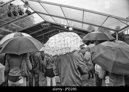 Un gruppo di persone con ombrelli sotto la pioggia durante un festival Foto Stock