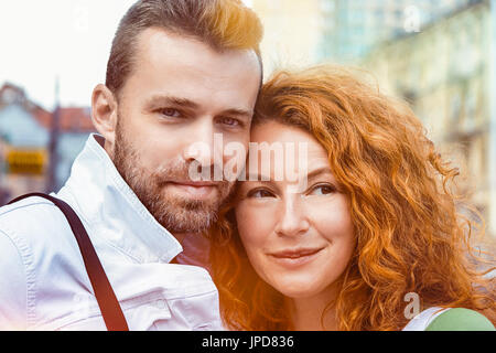 Persone di mezza età sposato l uomo e la donna in posa sulla fotocamera. Dai capelli rossi donna e uomo barbuto, street sunshine sfondo Foto Stock