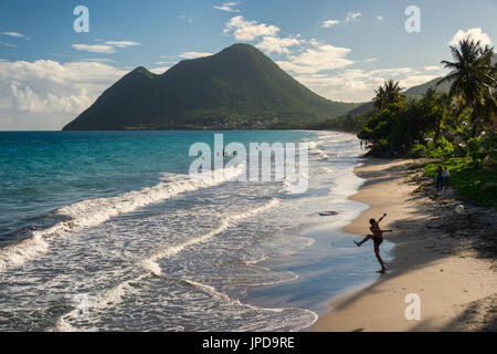 Le Diamant Beach in Martinica, con il giovane uomo giocando con una palla e la donna addormentata mountain in background Foto Stock