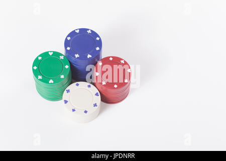 Quattro pile di colori diversi chip casino per piazzare scommesse sui tavoli di roulette e isolato su bianco con copyspace in un concetto di gioco d'azzardo Foto Stock