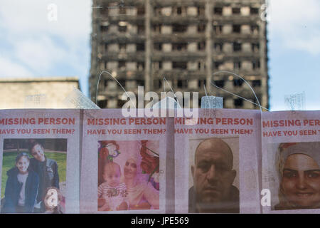 Una fermata degli autobus visualizza poster delle persone scomparse dopo il devastante incendio, i resti carbonizzati di grenfell torre può essere visto in background Foto Stock