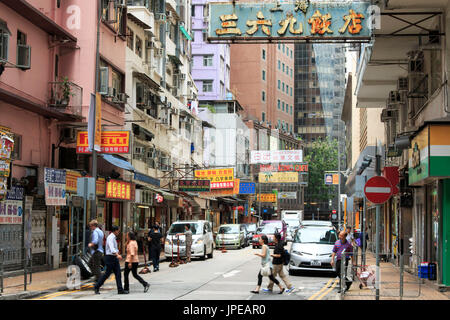 Dettaglio di una strada nel centro di Hong Kong con molte persone che camminano per la strada. Sullo sfondo i negozi e i ristoranti locali, Cina Foto Stock