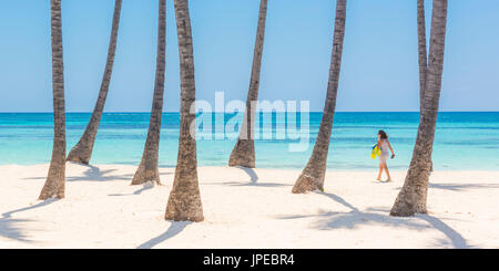 Spiaggia Juanillo (playa Juanillo), Punta Cana, Repubblica Dominicana. Donna di camminare sulla spiaggia orlata di palme (MR). Foto Stock