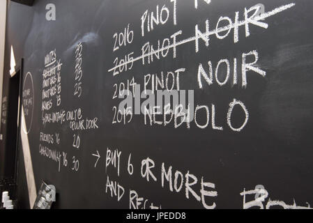 Un bianco e nero chalk board firmare con i tipi di vino e le annate in una sala degustazione vini in una cantina in arancione, NSW, Australia Foto Stock