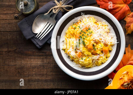 Risotto alla zucca con il timo e il formaggio parmigiano reggiano contro il legno scuro dello sfondo. Vista aerea Foto Stock