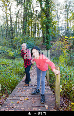 Coppia matura attraversando ponte in legno sul torrente Foto Stock